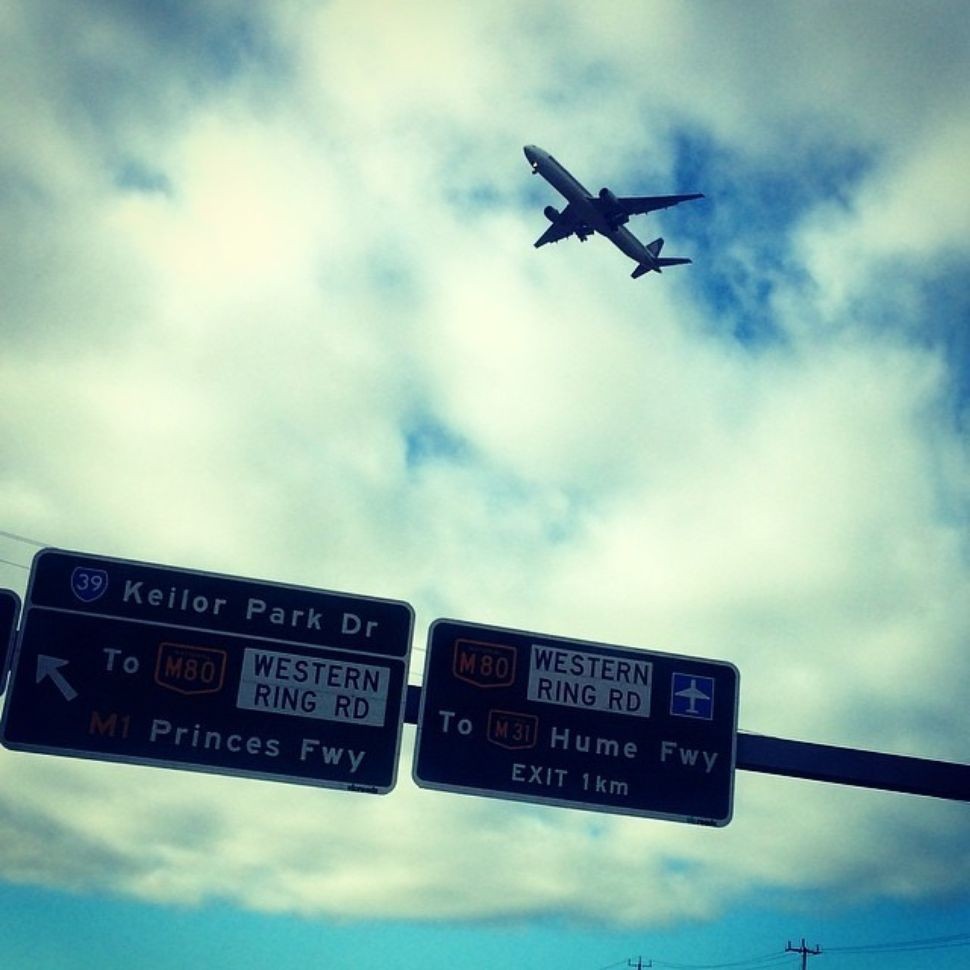 a plane flies over freeway signs