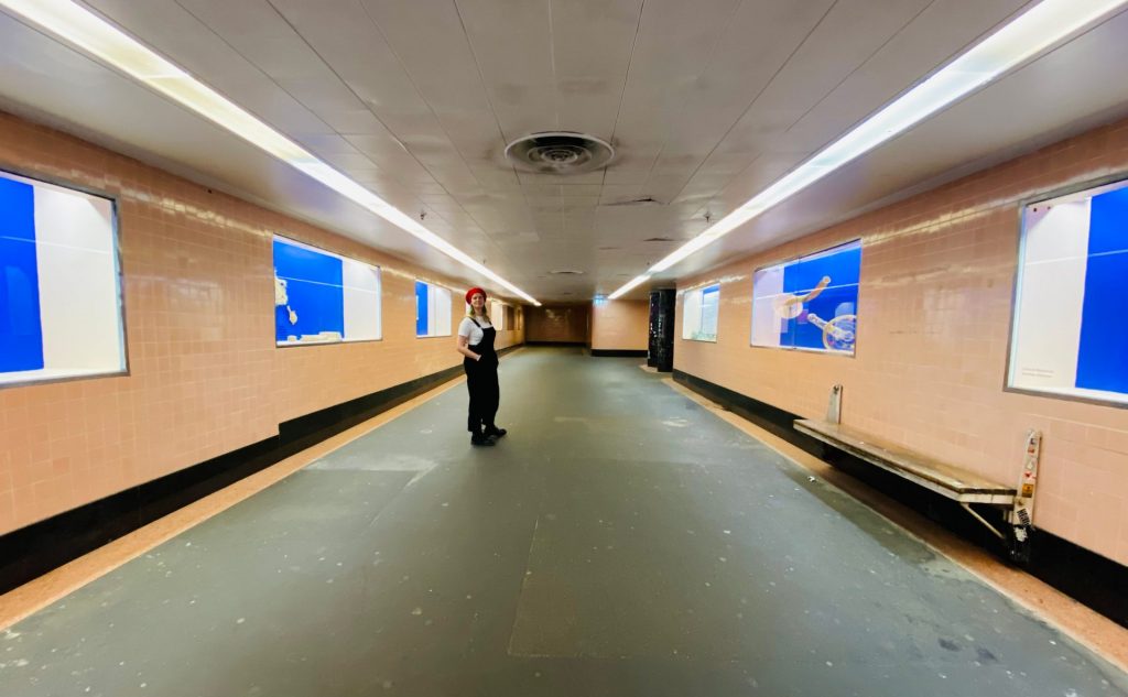 A woman stands in an empty subway