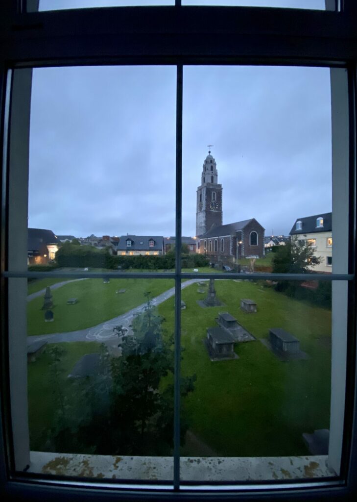 View from a window of a church tower and graveyard.